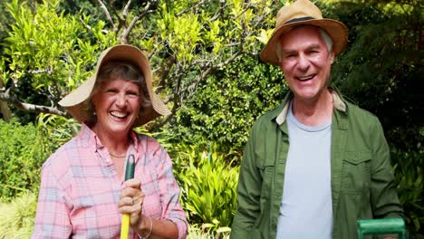 Happy-senior-couple-standing-with-gardening-tools-4k
