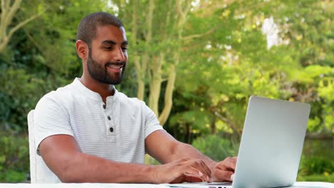 Smiling-man-using-laptop-in-garden-4k
