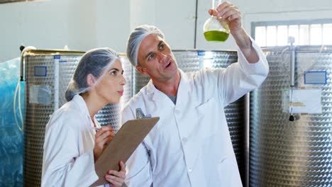 Technicians-writing-on-clipboard-while-examining-olive-oil-4k