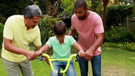 Father-and-grandfather-assisting-boy-to-ride-bicycle-4k