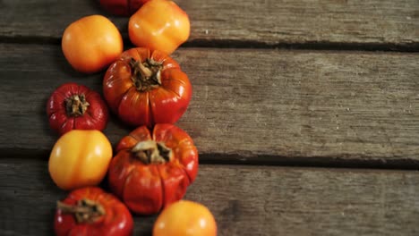 Small-pumpkins-and-tomatoes-on-a-wooden-table-4k