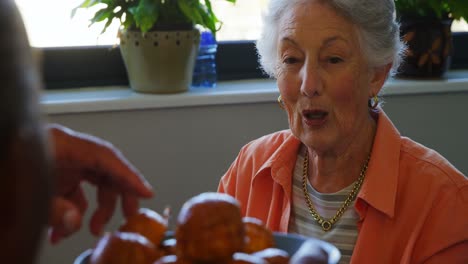 Senior-woman-taking-cupcake-from-tray-4k