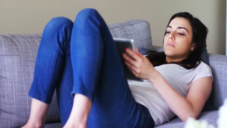Beautiful-woman-using-digital-tablet-while-relaxing-on-sofa-4k