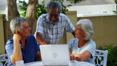 Glückliche-ältere-Freunde,-Die-Miteinander-Interagieren,-Während-Sie-Einen-4K-Laptop-Benutzen
