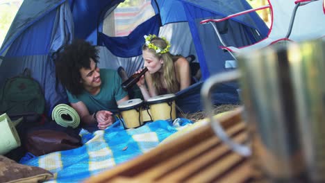 Couple-lying-on-tent-and-having-bottle-of-beer-4k
