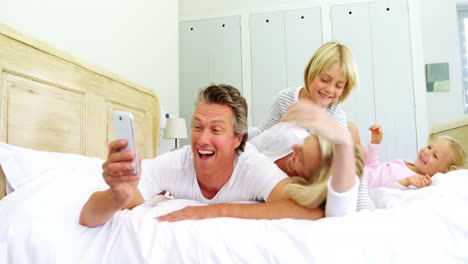 Happy-family-taking-a-selfie-on-mobile-phone-in-the-bed-room-4k