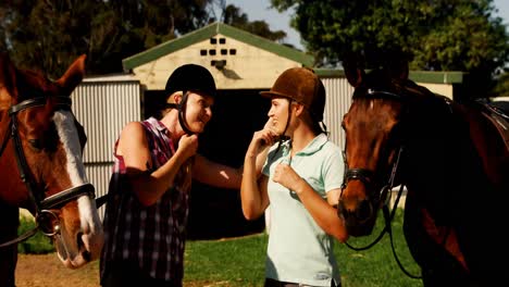 Friends-interacting-while-wearing-protective-helmet-in-ranch-4k