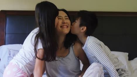Siblings-kissing-mother-on-cheeks-in-the-bed-room-4k