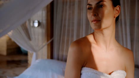Woman-in-towel-sitting-on-a-canopy-bed-in-cottage-4k