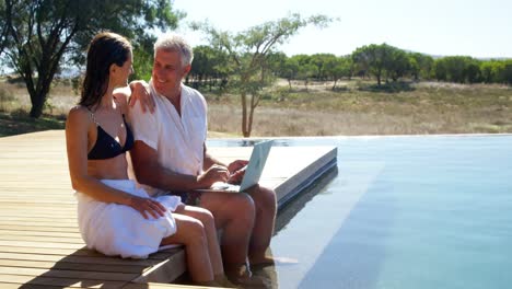 Couple-interacting-while-using-laptop-near-poolside-4k