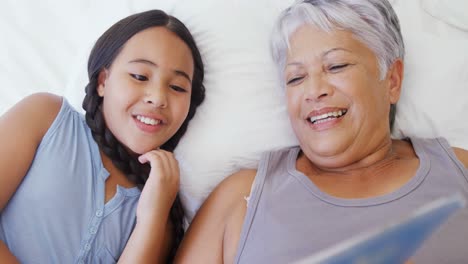 Grandmother-and-granddaughter-watching-photo-album-together-in-bed-room-4k