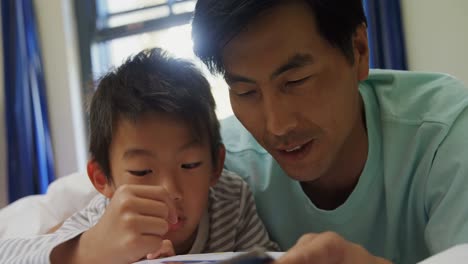 Happy-father-and-son-reading-story-book-on-bed-4k