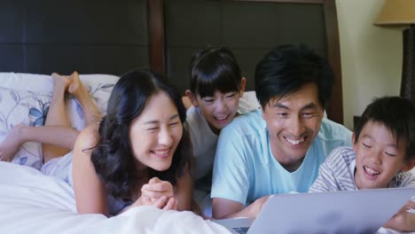 Family-having-fun-while-using-laptop-in-bedroom-4k