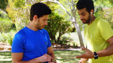 Two-male-joggers-interacting-with-each-other-in-park-4k