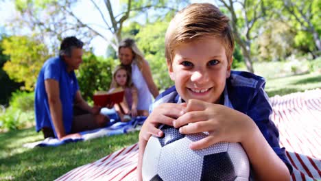 Lächelnder-Junge,-Der-Sich-Beim-Picknick-Im-Park-4k-Auf-Seinen-Fußball-Stützt