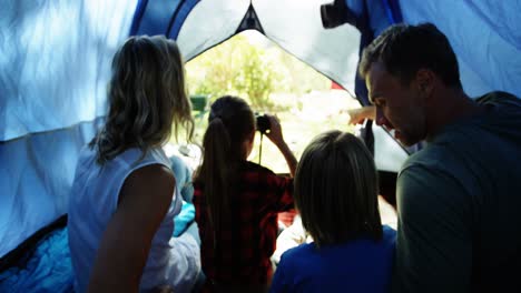 Family-looking-through-binoculars-while-sitting-in-the-tent-4k