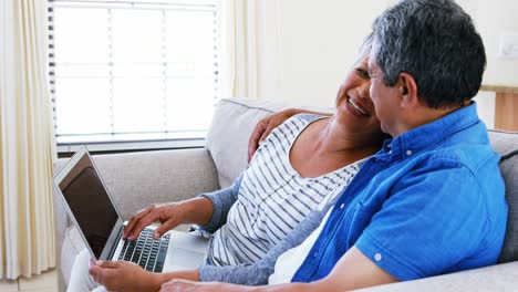 Senior-couple-using-laptop-in-living-room-4k