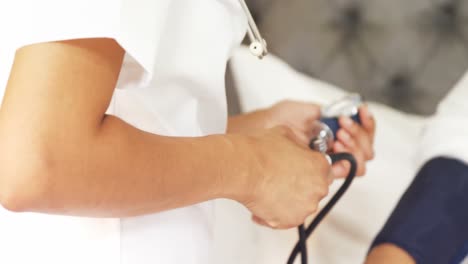 Female-doctor-measuring-blood-pressure-of-mature-woman-in-bedroom-4k