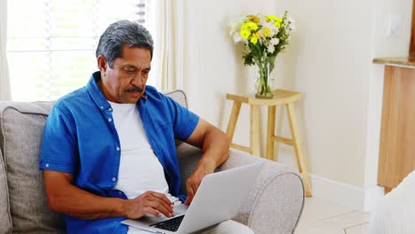Senior-man-using-laptop-in-living-room-4k