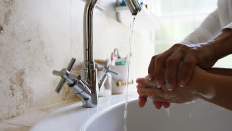 Grandmother-helping-her-granddaughter-to-wash-hands-in-bathroom-4k