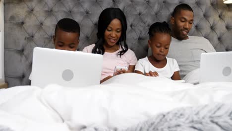 Familia-Usando-Dispositivos-Electrónicos-En-El-Dormitorio-4k