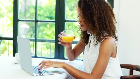 Woman-using-laptop-while-having-juice-4k
