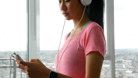 Woman-in-headphones-using-mobile-phone-at-home-4k