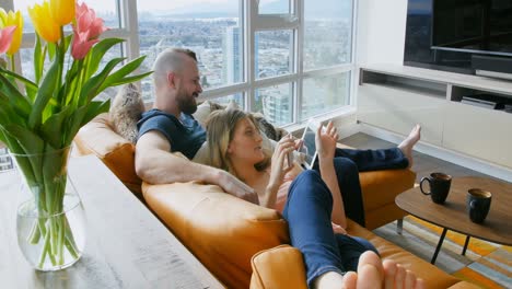 Couple-using-digital-tablet-and-mobile-phone-in-living-room-4k