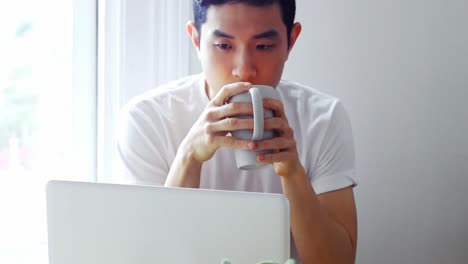Mann-Benutzt-Laptop,-Während-Er-Eine-Tasse-Kaffee-4k-Trinkt