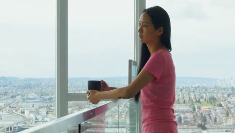 Woman-looking-through-window-while-having-cup-of-coffee-4k