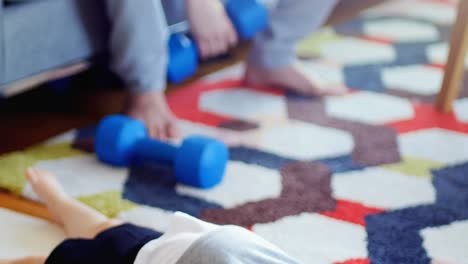 Father-exercising-while-baby-boy-lying-on-carpet-4k