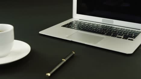Laptop,-coffee-and-pen-on-black-background-4k