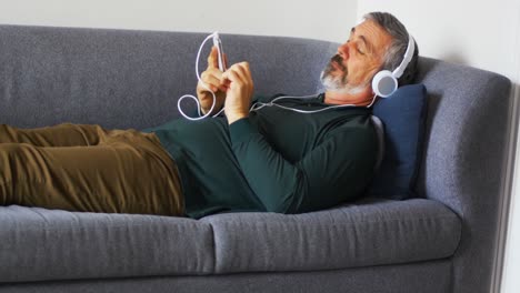 Mann-Hört-Musik-Auf-Dem-Mobiltelefon,-Während-Er-Auf-Dem-Sofa-Liegt-4k