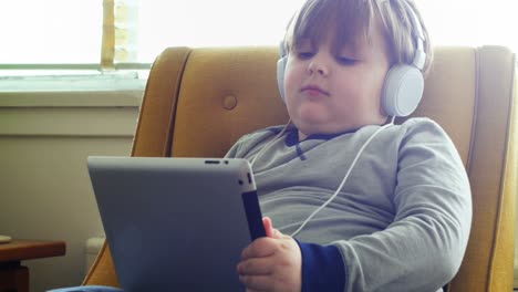 Junge-Mit-Kopfhörern-Nutzt-Digitales-Tablet-Im-Wohnzimmer-4k