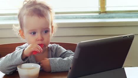 Baby-using-digital-tablet-while-having-breakfast-4k