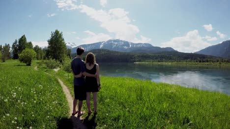 Couple-standing-with-arm-around-watching-beautiful-mountain-ranges4k
