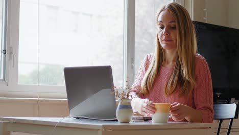 Woman-using-laptop-while-having-coffee-4k