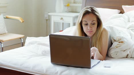 Woman-using-laptop-and-mobile-phone-on-bed-4k