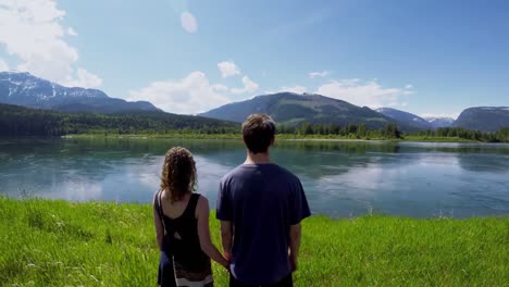 Couple-watching-beautiful-lake-surrounded-by-mountain-range-4k