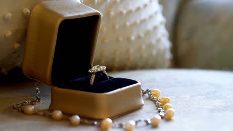 Wedding-ring-and-pearl-necklace-on-an-armchair-4K-4k
