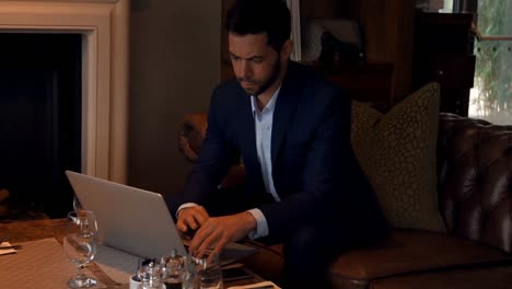 Businessman-using-laptop-at-dinning-table-4k