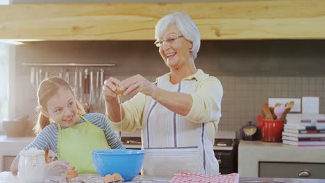 Grandmother-breaking-an-egg-in-bowl-and-little-girl-watching-4K-4k