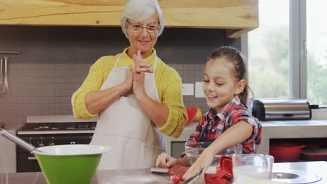 Excited-grandmother-talking-to-the-girl-while-preparing-cookies-4K-4k