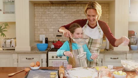 Smiling-mother-and-daughter-wearing-apron-sieving-flour-together-4K-4k