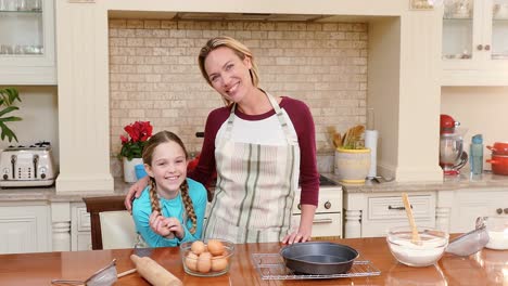 Smiling-mother-and-daughter-wearing-apron-standing-in-the-kitchen-4K-4k