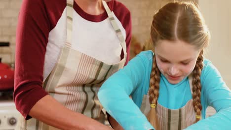 Happy-mother-and-daughter-wearing-apron-cutting-dough-4K-4k