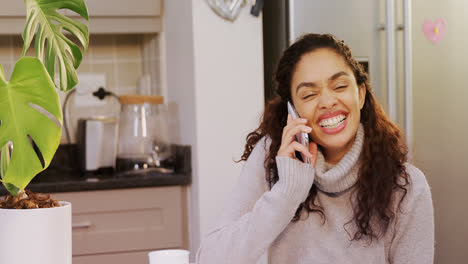 Woman-wearing-winter-cloths-laughing-while-talking-on-phone-in-kitchen-4K-4k