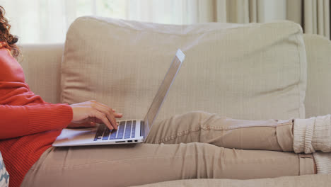 Thoughtful-woman-sitting-on-sofa-working-on-her-laptop-4K-4k