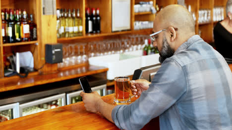 Hombre-Usando-Teléfono-Móvil-Mientras-Toma-Cerveza-En-El-Mostrador-4k