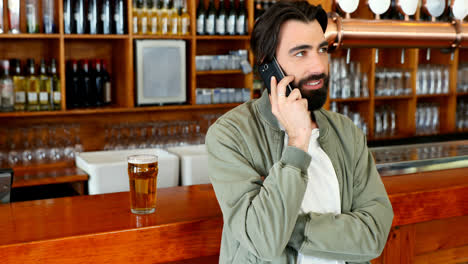 Smiling-man-talking-on-mobile-phone-at-counter-4k